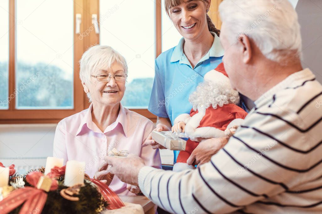 Seniors in nursing home exchanging presents for Christmas
