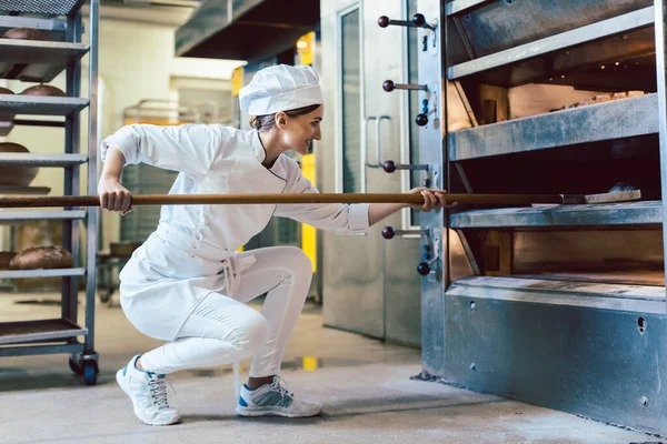 Padeiro colocando pão no forno da padaria — Fotografia de Stock