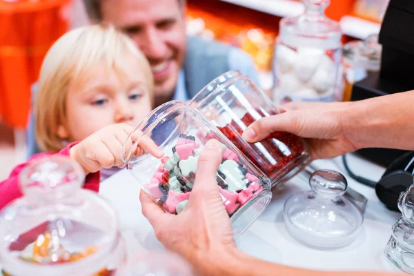 Bambino afferrando alcuni dolci da un barattolo nel negozio di caramelle — Foto Stock