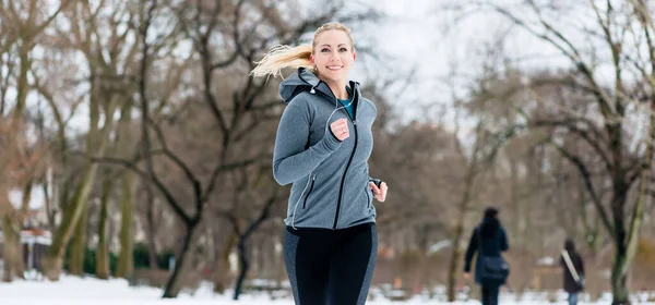 Mujer corriendo por un camino en el día de invierno en el parque —  Fotos de Stock