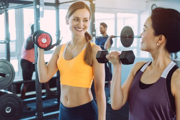 Spor salonunda birlikte fitness eğitimi yapan iki kadın
