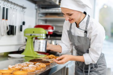 Patissier küçük kek üzerine kakao tozu koyarak