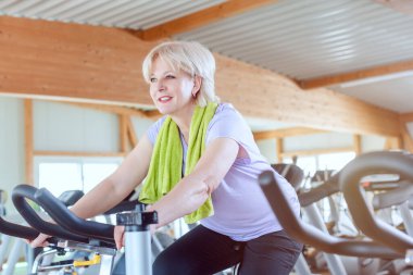 Son sınıf öğrencisi spor salonunda bisiklette daha iyi spor yapmak için egzersiz yapıyor.