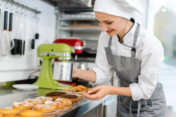 Patissier legt Kakaopulver auf kleine Kuchen — Stockfoto