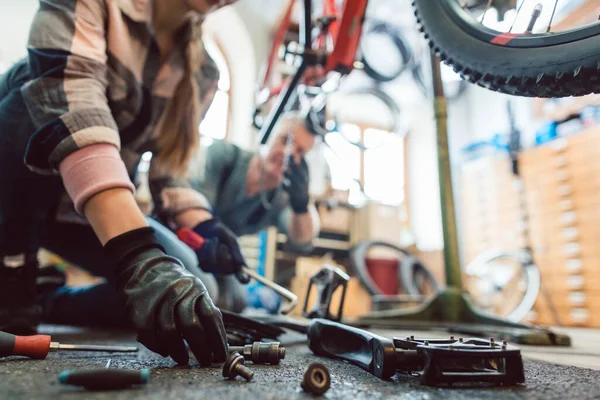 Bike mechanic working on a bicycle getting her tools — Stock Photo, Image