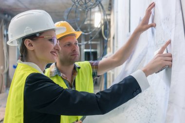 Bina planına bakan inşaat işçisi ve inşaat işçisi