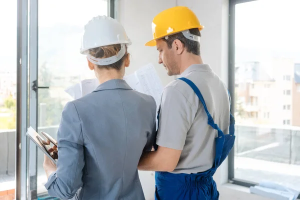 Trabalhador da construção civil e arquiteto olhando para o plano no local — Fotografia de Stock