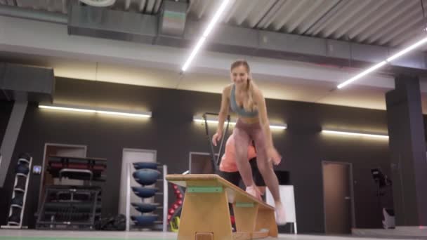 Παραδοσιακή προπόνηση βήμα στο γυμναστήριο από λεπτό και μεγάλο κορίτσι — Αρχείο Βίντεο