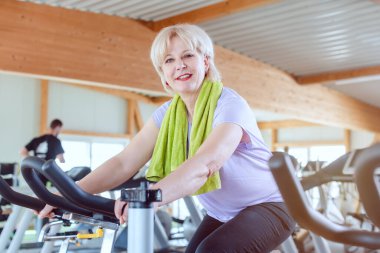 Son sınıf öğrencisi spor salonunda bisiklette daha iyi spor yapmak için egzersiz yapıyor.