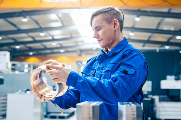 Lehrling in der Metallbearbeitung schaut sich Werkstück an — Stockfoto