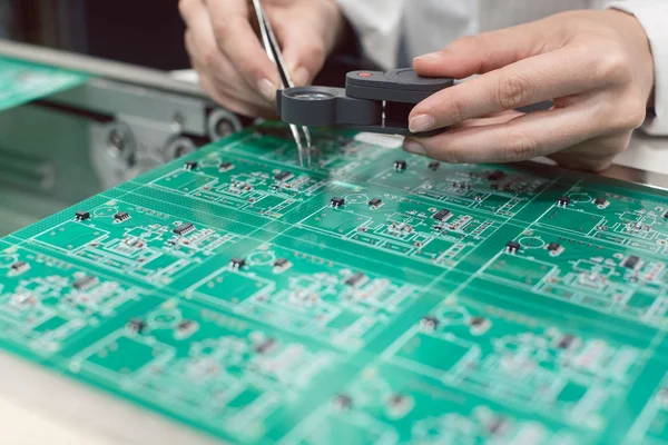 Técnico que insere componentes eletrônicos em um PDB para montagem — Fotografia de Stock