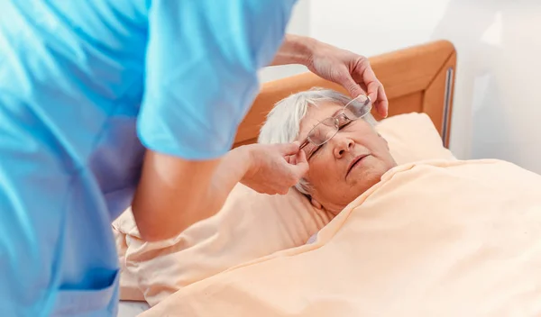 Infermiera prendersi cura di dormire donna anziana nella casa di cura — Foto Stock