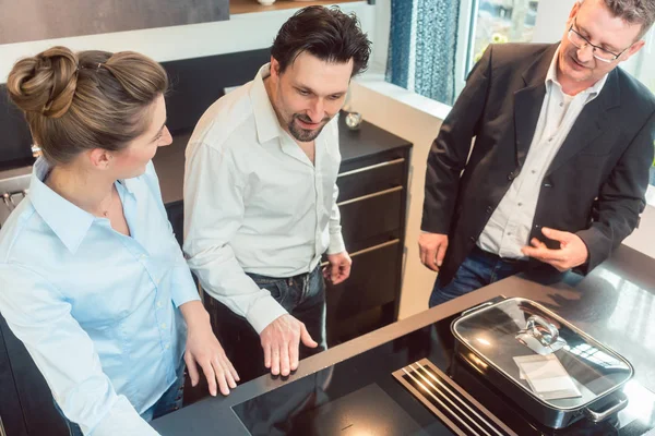 Salesman explaining details of new kitchen to couple — Stock Photo, Image