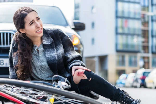 Young woman suffering severe pain after falling down from her bicycle