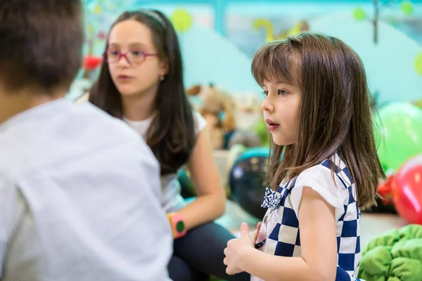 Ragazza timida guardando i suoi compagni di giochi che interagiscono in un asilo moderno — Foto Stock