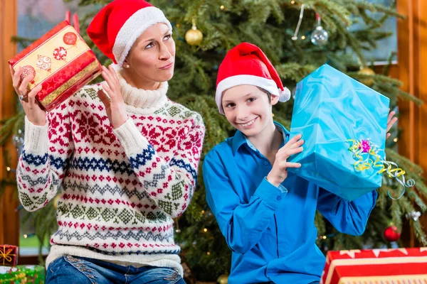 Femme et enfant à Noël avec des cadeaux emballés et des casquettes de Père Noël — Photo