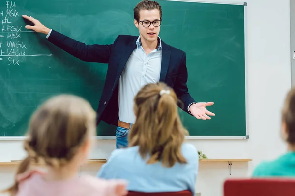 Nauczyciel stoi przed uczniów w szkole Klasa — Zdjęcie stockowe