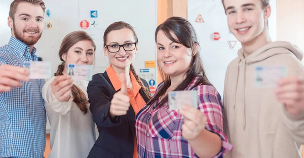 Sürücü eğitmeni ve öğrenciler yeni ehliyetlerini gösteriyor. — Stok fotoğraf