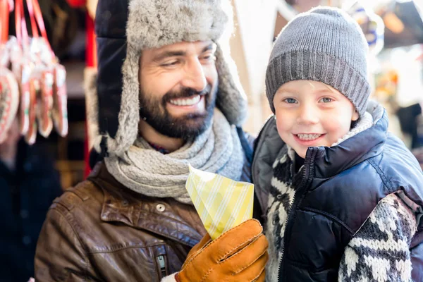 クリスマスマーケットでお菓子を食べる父と息子 — ストック写真