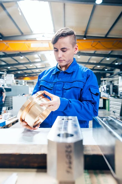 Lehrling in der Metallbearbeitung schaut sich Werkstück an — Stockfoto