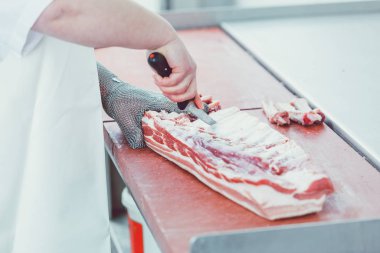 Butcher cutting meat for further processing with knife clipart