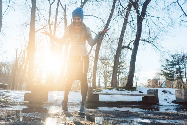 Woman having to step into a puddle of water and thawing snow — Stock Photo, Image
