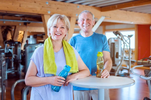 Dos personas mayores tomando un descanso de hacer ejercicio en el gimnasio — Foto de Stock