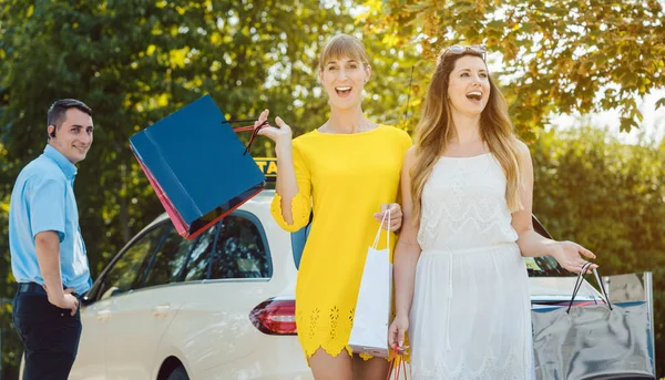 Mulheres com sacos de compras saindo de táxi — Fotografia de Stock