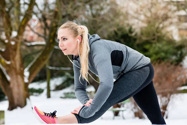 Mujer haciendo deportes al aire libre estirando sus piernas en la nieve día de invierno — Foto de Stock