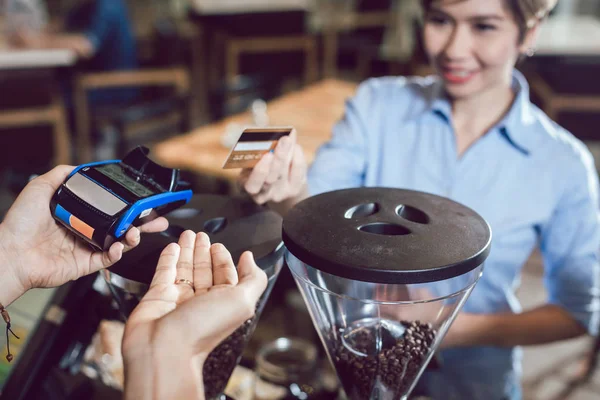 Cliente pagando por seu pedido com um cartão de crédito em um café — Fotografia de Stock