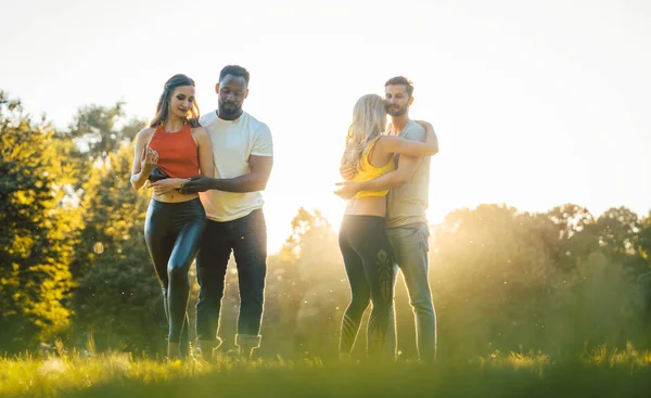 Dois casais dançando kizomba durante o pôr do sol em um parque — Fotografia de Stock