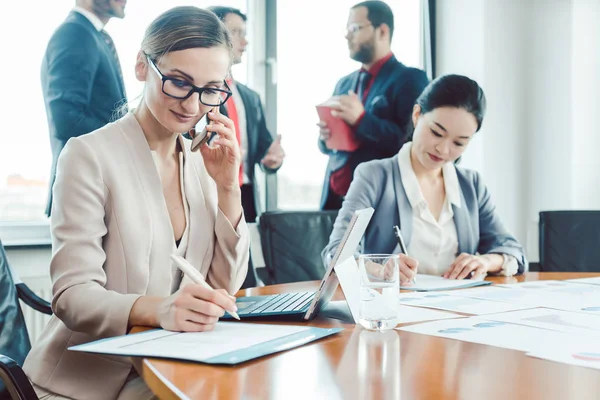 Zakenvrouw werken terwijl de mannen zijn chatten werkloos — Stockfoto