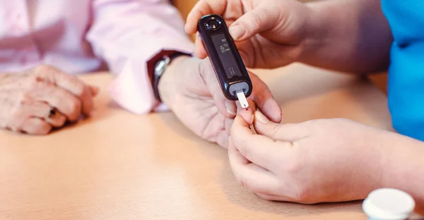 Enfermeira administra teste de diabetes para idosos em casa de repouso — Fotografia de Stock