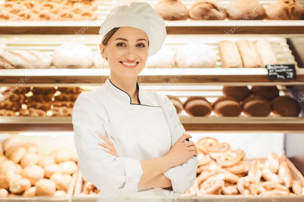Sales woman in bakery shop standing in front of delicious bread