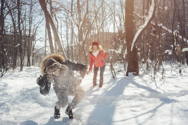 冬天，女人带着嬉闹的心情向她的男人扔雪球 — 图库照片