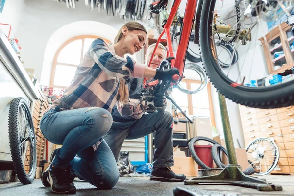 Dans un atelier de réparation de vélo avec deux mécaniciens de vélo — Photo