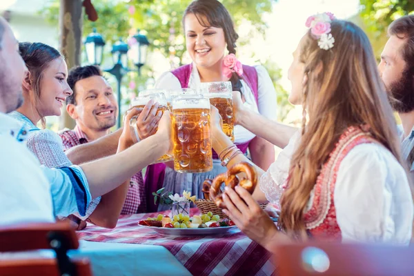 Amigos alegres brindando en el jardín de cerveza bávaro — Foto de Stock