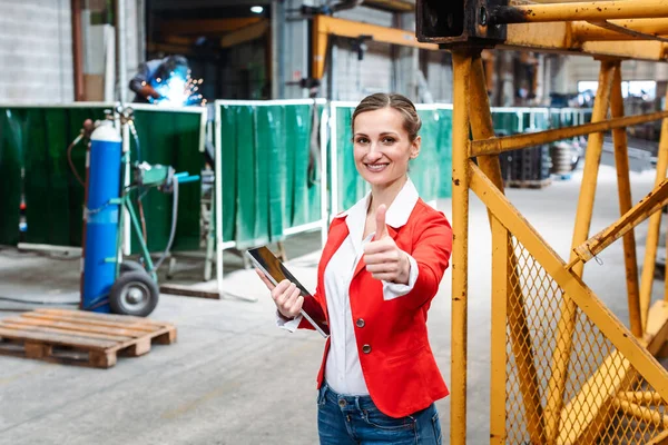 Mujer mostrando pulgares hacia arriba en la fábrica de metal —  Fotos de Stock