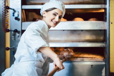 Baker fırına ekmek koyuyor.