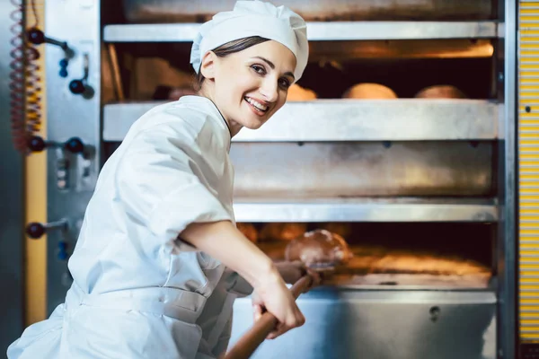 Baker menempatkan roti dalam oven toko roti — Stok Foto