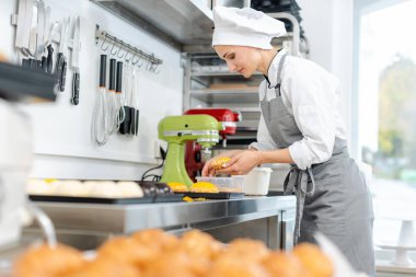 Şekerci küçük tatlı kekler üzerinde çalışıyor.
