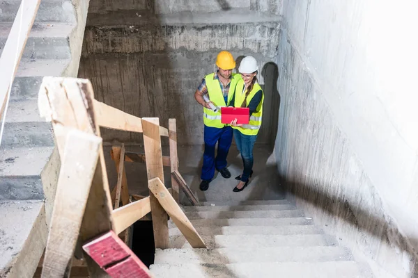 Bauarbeiter und Bauarbeiter inspizieren Treppe im Rohbau — Stockfoto