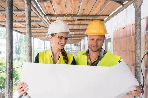 Byggnadsarbetare och byggmästare på byggnadsställningar läser planen — Stockfoto
