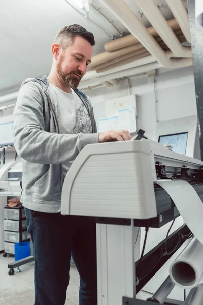 Hombre preparando impresora de gran formato para un trabajo de impresión —  Fotos de Stock