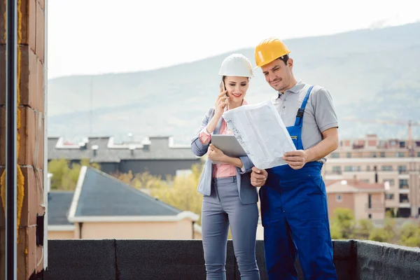 Trabajador y promotor en obra investigando el plan — Foto de Stock