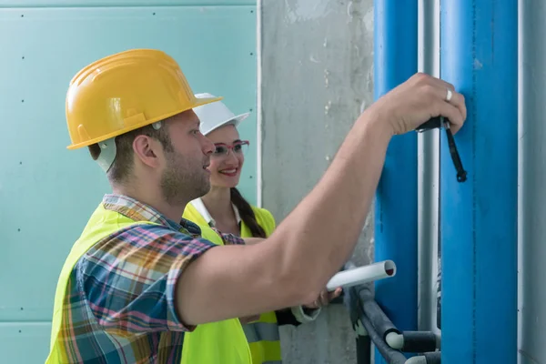 Construction workers measuring pipes on site — Stock Photo, Image