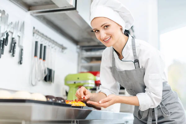 Chef de pastelaria colocando cranberries em cima de pequenas tarteletes — Fotografia de Stock