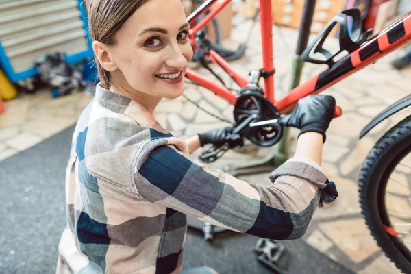 Mulher feliz trabalhando como mecânico de bicicletas — Fotografia de Stock