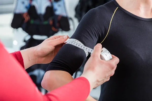 Trenér měření biceps sval ženy v ems tělocvična — Stock fotografie