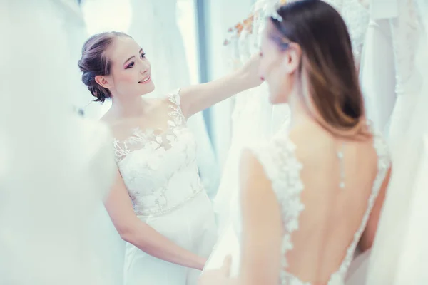 Dos novias comprando vestido de novia en la tienda divirtiéndose — Foto de Stock